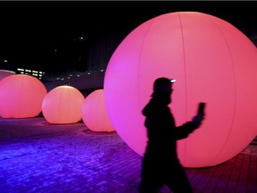 A man shoots video of himself as he runs past the Nouvelle Lune light and sound installation in the Quartier des Spectacles in Montreal Monday December 14, 2020.