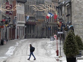 A lone pedestrian walks in Place Jacques-Cartier at Saint-Paul Street in Old Montreal on Tuesday, December 22, 2020.