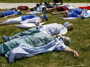 Saying they're "dead from fatigue," health care workers hold a die-in during a demonstration outside Maisonneuve-Rosemont Hospital in Montreal Wednesday May 27, 2020.