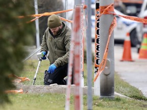 A Sûreté du Québec crime scene technician uses a metal detector at the scene of a homicide in Laval Dec. 3, 2020.
