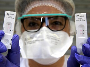 A health worker shows a negative (L) and a positive (R) Covid-19 antigen rapid test on December 17, 2020 at the gymnasium of Vrigne-aux-Bois, northern France, near Charleville-Mezieres as the city launched a mass drive to test inhabitants.