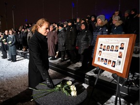 Governor General Julie Payette lays a white rose in front of a photo showing the 14 women who were killed in the 1989 Polytechnique massacre, during a vigil on top of Mount Royal marking the 30th anniversary of the mass killing, on December 6, 2019.