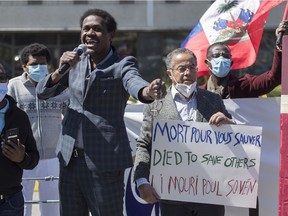 Wilner Cayo, centre, and Frantz Andre attend a demonstration outside Prime Minister Justin Trudeau's constituency office in Montreal on May 23, 2020, where they called on the government to give residency status to migrant workers as the COVID-19 pandemic continues in Canada and around the world.