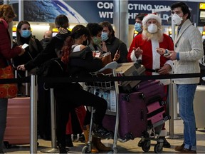 Travellers, one dressed in a Father Christmas outfit and all wearing face coverings, queue with their luggage in the departures hall at Terminal 2 of Heathrow Airport in west London on December 21, 2020, as a string of countries around the world banned travellers arriving from the UK, due to the rapid spread of a new, more-infectious coronavirus strain. - Prime Minister Boris Johnson was to chair a crisis meeting Monday as a growing number of countries blocked flights from Britain over a new highly infectious coronavirus strain the UK said was "out of control".