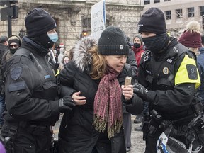 Police detain a woman during a demonstration in Montreal, Sunday, December 20, 2020, where people protested measures implemented by the Quebec government to help stop the spread of COVID-19.