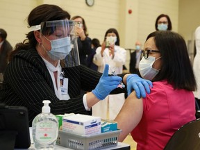 Tamara Dus injects health-care worker Cecile Lasco with the Pfizer/BioNTech vaccine in Toronto on Monday. Because there was a problem with the needle's connection to the vial, some of the vaccine leaked out.