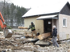 Volunteers pull out a tree that fell through a cabin at a campground, in Ste-Brigitte-de-Laval, Que., Saturday, Dec. 26, 2020. A flash flood forced the evacuation of residents on Dec. 25, as the waters of the Montmorency river came up because of heavy rains.
