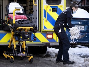 An Urgences-santé paramedic shovels snow to be able to get a stretcher to the sidewalk in Montreal on Thursday, December 31, 2020.