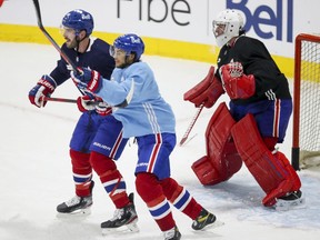 Canadiens newcomers Joel Edmundson, left, and Michael Frolik battle for position in front of goalie Carey Price during training-camp practice Monday at the Bell Sports Complex in Brossard.