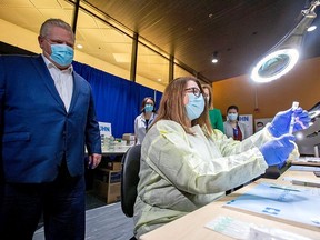Ontario Premier Doug Ford watches a health-care worker prepare a Pfizer/BioNTech vaccine at the Michener Institute in Toronto Monday.