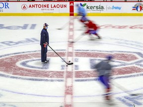 Canadiens head coach Claude Julien stands at centre ice as players skate around him during training-camp practice at the Bell Sports Complex in Brossard.