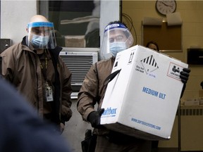 UPS driver Angelo Aranitis, right, delivers the first box of Covid-19 vaccinations at Maimonides in Montreal on Monday, Dec. 14, 2020.