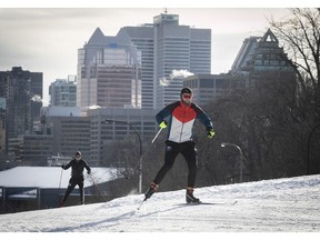Cross-country skiers take in an early morning run on Mount-Royal park with the city skyline in the background on Sunday, January 10, 2021.