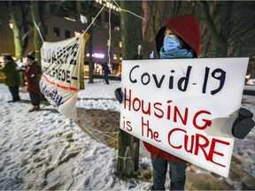 Ines Benessaiah of Popir comité logement holds a sign during news conference by community groups to talk about the impact of the province's curfew on homeless people in Montreal Monday January 11, 2021.