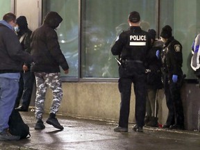 Police talk with homeless people outside the shelter in Hotel Place Dupuis shortly before the province's curfew came into effect on Monday.