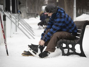 Gennaro Patduano laces his skates  before getting on the hockey rink at Parc Lafontaine with his son on Thursday, January 14, 2021.