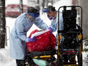 Urgences-santé paramedics fight with snow and cold as they load an elderly "COVID-19 suspect" case in to an ambulance in Montreal, on Saturday, Jan. 16, 2021.