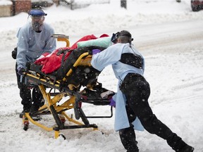 Urgences-sante paramedics fights with snow and cold as they load an elderly "Covid-19 suspect" case in to an ambulance in Montreal, on Saturday, January 16, 2021.