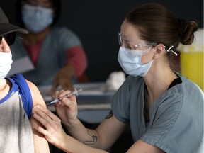 A COVID-19 vaccination is administered to a homeless man in Montreal on Tuesday, Jan. 19, 2021.