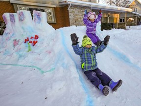 Cousins Darius Paleos, left, and Kai Kaluzny throw their arms in the air as they slide down from the Paleos's snow fort in Beaconsfield, west of Montreal.
