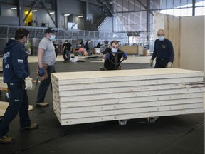 Workers move equipment on the indoor soccer field at the Stade de soccer de Montréal on Jan. 21, 2021, to create a temporary installation that will house 150 COVID-positive homeless people.