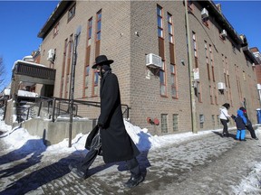 A Hasidic Jew walks past a synagogue at the corner of Hutchison and St. Viateur Sts. in the Outremont borough of Montreal Jan 24, 2021.