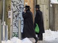 A couple of Hasidic Jews enter the rear entrance of a synagogue at the corner of Hutchison and St. Viateur Sts. in the Outremont borough of Montreal on Sunday Jan. 24, 2021. Montreal Police intervened at the synagogue the day before to break a gathering of more than the 10 people who are allowed in houses of worship under the Quebec government's latest coronavirus regulations.
