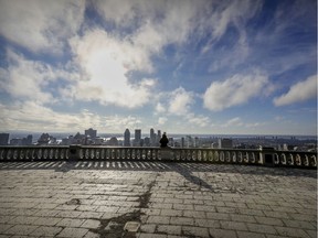 A woman looks at downtown Montreal from the lookout on Mount Royal Wednesday April 1, 2020. "We benefit uniquely from living with two of the world’s great languages and cultures," Joan Fraser writes.