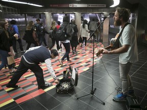 Commuter helps out musician Greg Halpin while he performs at the Guy-Concordia métro station on Oct. 6, 2017. With the COVID-19 restrictions, buskers have no means to make a living.