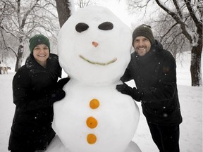 The creators of a large snowwoman pose with their work before leaving Parc Lafontaine on Jan. 16, 2021.