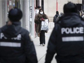 A man talks with a police officer after being issued a fine during a demonstration in Montreal, Sunday, Dec. 20, 2020.