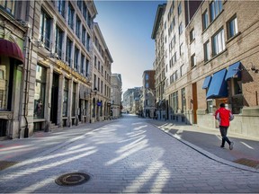 A man runs down empty St-Paul St. in Old Montreal on Tuesday, Dec. 29, 2020 as non-essential businesses in Quebec are locked down until January 11, 2021.