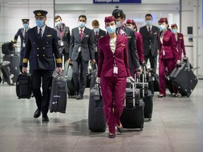 Qatar Airways flight crew walk through the arrivals area after landing at Trudeau airport in Montreal on Wednesday, Dec. 30, 2020.