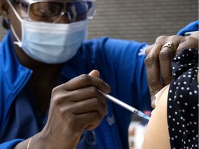 Nurse Gina Valcourt administers the Pfizer-BioNTech COVID-19 vaccine.