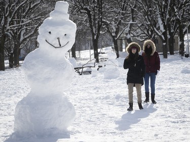 Laurianne Bezier, left, and Coralie Banon gets a closer look at the snowmen and snow sculptures in Jeanne-Mance Park on Monday, Jan. 18, 2021.