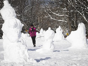 Laurence Laffaille gets a closer look at the snowmen and snow sculptures in Jeanne-Mance Park on Monday, Jan. 18, 2021.