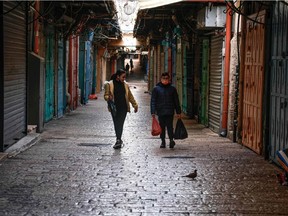 Palestinian children walk past closed shops in the old city of Jerusalem on Dec. 28, 2020, during Israel's third COVID-19 coronavirus lockdown.