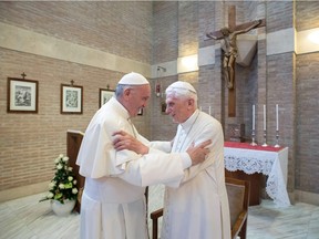 (FILES) This handout picture released on February 15, 2018 by the Vatican press office shows Pope Francis (L) greeting Pope Benedict XVI at the Vatican. - Both Pope Francis and his predecessor, former pope Benedict XVI, have received the coronavirus vaccine, the Vatican said on January 14, 2021.