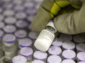 A picture taken on January 15, 2021, shows a pharmacist holding with gloved hands a phial of the undiluted Pfizer-BioNTech vaccine for Covid-19, stored at -70 ° in a super freezer of the hospital of Le Mans, northwestern France as the country carry on a vaccination campaign to fight against the spread of the novel coronavirus. - After dilution the vial contains five doses of 0,3ml for intramuscular use.