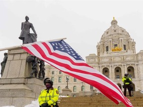 Police officers stand guard during a small gathering of Trump supporters outside the Capitol building in St. Paul, Minn., on Saturday, Jan. 16, 2021. The inauguration of Joe Biden is taking place amid unprecedented security following the Jan. 6 storming of the Capitol by supporters of President Donald Trump while Congress was certifying Biden's Nov. 3, 2020, election victory. Security officials have warned armed extremist Trump supporters, possibly carrying explosives, pose a threat to Washington as well as state capitals over the coming week.