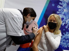 An Israeli health worker administers a dose of the Pfizer-BioNtech Covid-19 vaccine to a woman at Clalit Health Services, in the hallways of the Netanya stadium, on January 20, 2021 in the Israeli coastal city of Netanya.