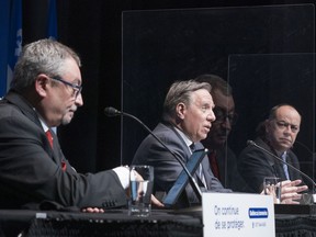 Premier François Legault responds to a question flanked by Health Minister Christian Dubé, right, and Dr. Horacio Arruda, Quebec's director of public health, during a news conference in Montreal, on Wednesday, January 6, 2021.