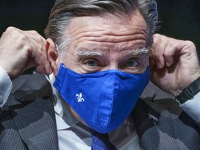 Quebec Premier Francois Legault slips on his mask following a news conference in Montreal, on Tuesday, January 19, 2021.
