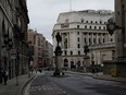 A man stands near a bus stop in the City of London financial district in London, Jan. 5, 2021, on the first morning of England entering a third national lockdown since the coronavirus outbreak began. British Prime Minister Boris Johnson on Monday night announced a tough new stay-at-home order that will last at least six weeks, as authorities struggle to stem a surge in COVID-19 infections that threatens to overwhelm hospitals around the U.K.