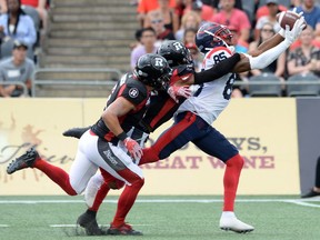Montreal Alouettes receiver B.J. Cunningham hauls in a pass as Ottawa Redblacks' Antoine Pruneau, left, and Corey Tindal Sr. defend during first quarter on July 13, 2019, in Ottawa.
