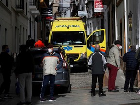 People stand near an ambulance as healthcare workers treat a patient suffering from the coronavirus disease (COVID-19) during a home visit, amid the coronavirus disease (COVID-19) outbreak, in Ronda, southern Spain January 23, 2021. REUTERS/Jon Nazca