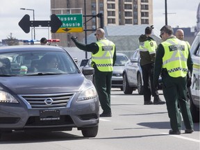 Sûreté du Québec officers stop vehicles on the Macdonald-Cartier Interprovincial Bridge as they entered Gatineau from Ottawa, to check for drivers and passengers possibly infected with COVID-19 in April 2020.