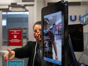 A United Airlines employee helps a passenger position himself as he uses biometric boarding to board an international flight from IAH George Bush Intercontinental Airport amid the coronavirus disease (COVID-19) outbreak in Houston, Tex., on July 21, 2020.