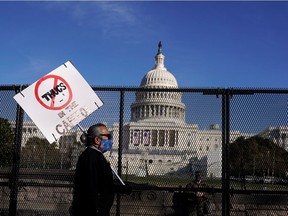 A pedestrian carries a sign opposing supporters of U.S. President Donald Trump who stormed the U.S. Capitol in Washington, U.S., January 10, 2021.      REUTERS/Joshua Roberts