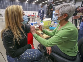 Annie Dufour, left, media relations person for the CIUSSS Centre-Sud, sits for a simulated vaccination from veterinarian Christine Vézina during media tour of new mass vaccination clinic at the Palais des Congrès in Montreal Monday February 1, 2021.